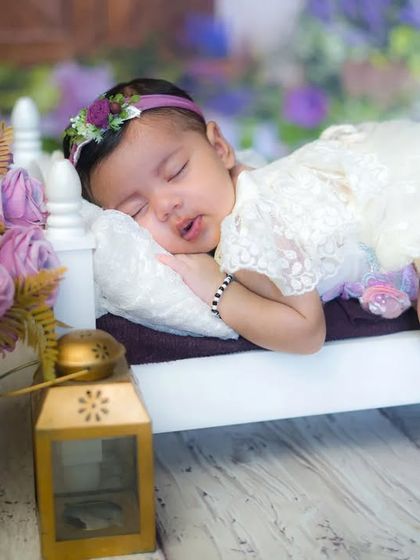 A sleeping princess in a field of lavender. This beautiful setup with purple flowers and a tiny bed creates a dreamy and magical newborn portrait.