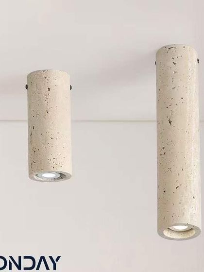 A pair of cylindrical surface-mounted lights made from travertine. These are a great option for rooms with lower ceilings where a pendant won't fit.