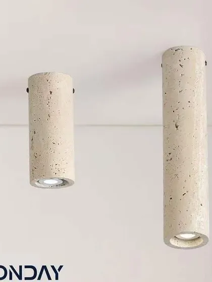 A pair of cylindrical surface-mounted lights made from travertine. These are a great option for rooms with lower ceilings where a pendant won't fit.