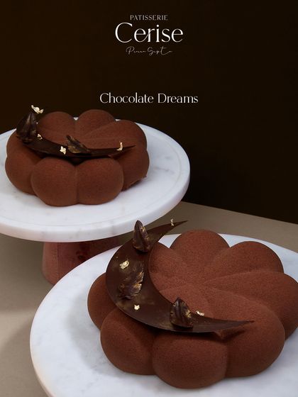 My Chocolate Dreams entremet, presented as a pair of mini desserts. The elegant flower shape and delicate chocolate garnish make it a visually stunning treat.