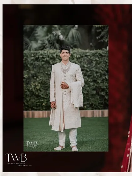 A classic portrait of the groom in his elegant white sherwani. He stands proudly, ready to meet his bride, looking calm and happy.