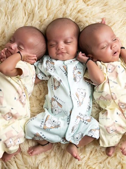 A more candid shot of the triplets in matching onesies, stretching and sleeping together. These natural moments are just as precious.