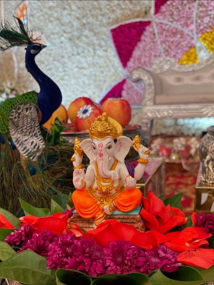 A beautiful Ganesha idol adorned with red flowers, serving as a focal point on the offering table.