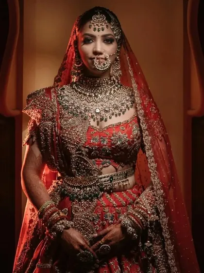 A full-length bridal portrait showcasing the magnificent red lehenga and intricate jewelry. We use careful lighting to make sure every detail of the bride's look is captured perfectly.
