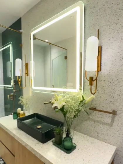 Green and gold is a timeless combination for luxury. In this bathroom, a deep green vessel sink and matching accessories pop against a terrazzo-style wall, while gold sconces and fixtures add a touch of glamour.