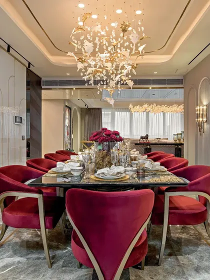 A dining table set for a feast, with bold red velvet chairs and a sculptural chandelier. This space is a masterclass in craftsmanship, designed for memorable gatherings.