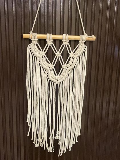 A smaller, simpler macrame wall hanging, perfect for narrow walls or for grouping with other art. It features a diamond pattern and a clean, straight fringe.