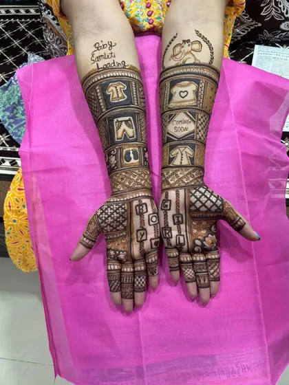A closer look at the details in this custom Godh Bharai mehndi. You can clearly see the baby clothes, the 'Coming Soon' message, and the playful 'Baby Loading' text on the forearm.