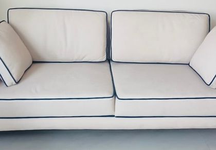 A full view of our Linear Sofa, showcasing its crisp white upholstery and contrasting black piping. This three-seater sofa is perfect for creating a modern and graphic statement in a living room.
