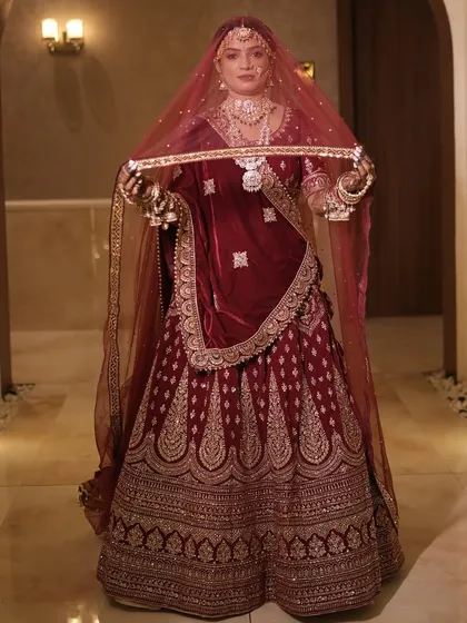 A full-length shot of this magnificent bride in her velvet maroon lehenga. The entire look is styled to create a royal and timeless bridal portrait.