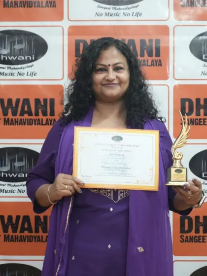 An adult student proudly holds her certificate and trophy.
