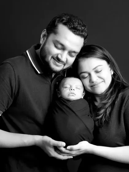 We believe these first family portraits are priceless. This classic black and white shot captures the pure love and connection between new parents and their sleeping baby, a memory to cherish forever.
