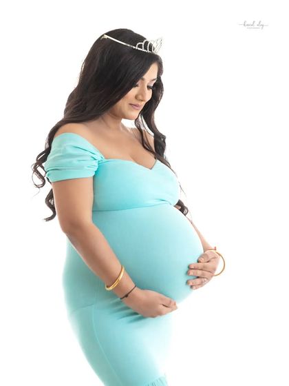 A serene profile shot of an expecting mother cradling her bump. The simple composition and white background make for a timeless and elegant maternity photograph.