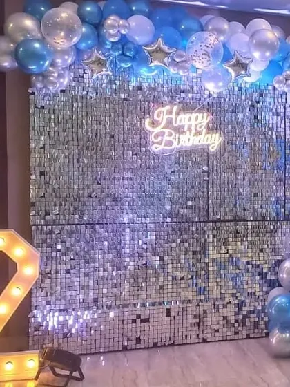 A stunning silver sequin wall backdrop for a 2nd birthday, framed by a blue, silver, and white balloon arch.