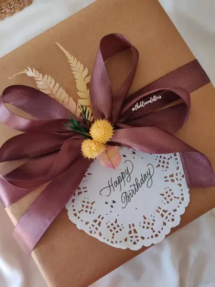 The final touch to a thoughtful gift. A beautifully wrapped present with a hand written 'Happy Birthday' tag, complete with dried foliage for a rustic and elegant look.