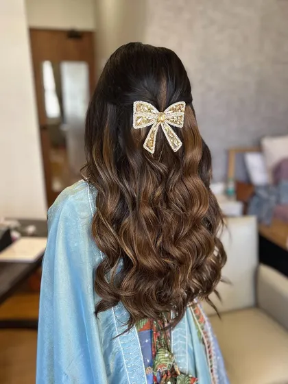 The embellished bow adds a touch of glamour to this simple half updo. It's a great way to elevate a classic hairstyle.