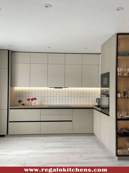 This cozy L-shaped kitchen features light wood cabinetry and an illuminated glass display case. The design makes excellent use of a compact space, providing ample storage and a functional work area with a clean, modern aesthetic.