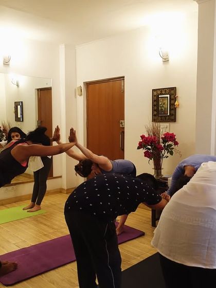 A group of students practicing a forward fold variation together. This pose is excellent for stretching the hamstrings and releasing tension in the back.