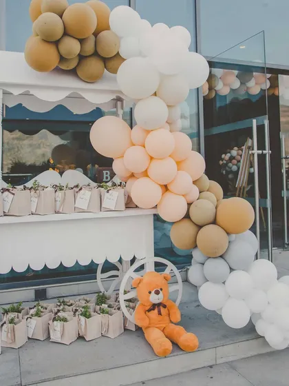 A gift and favor cart for the baby shower, decorated with a beautiful cascade of pastel-colored balloons.