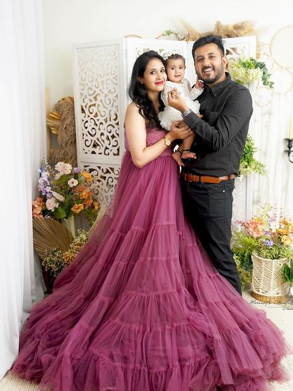 A family of three dressed in elegant outfits. The mother's flowing mauve gown is simply breathtaking, creating a fairytale-like family portrait.