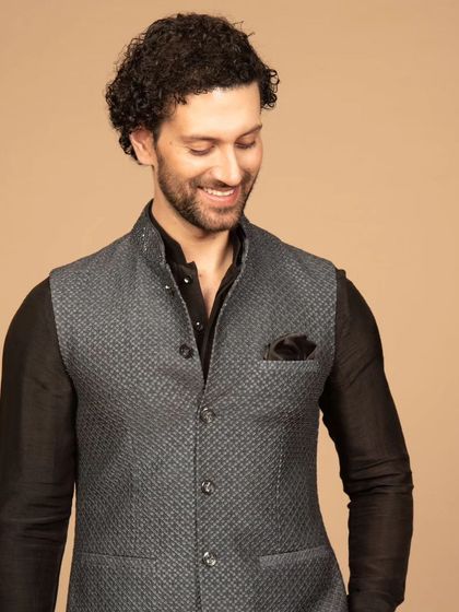 A closer look at the grey textured Nehru jacket, highlighting the subtle pattern and the clean, structured tailoring. The black pocket square adds a sharp, contrasting detail.