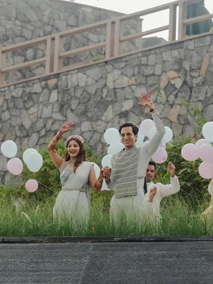 A grand, celebratory entrance, waving to their loved ones, with balloons adding to the festive atmosphere.