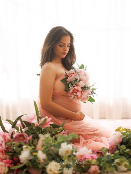 A beautiful high-key shot, with the mother-to-be surrounded by flowers, creating a soft and romantic atmosphere.
