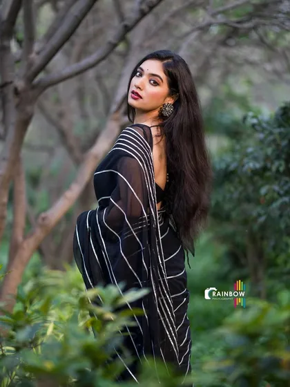 A classic pose in a black striped saree, with the model looking back elegantly.