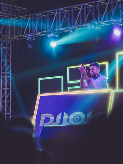 A shot of me at the decks, framed by the impressive lighting rig and custom visuals of a large festival stage.