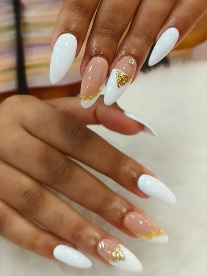 Clean lines and luxurious details define this look. Crisp white stiletto extensions provide the perfect canvas for a negative space design accented with shimmering gold foil. This style is a testament to our precision and minimalist glamour.
