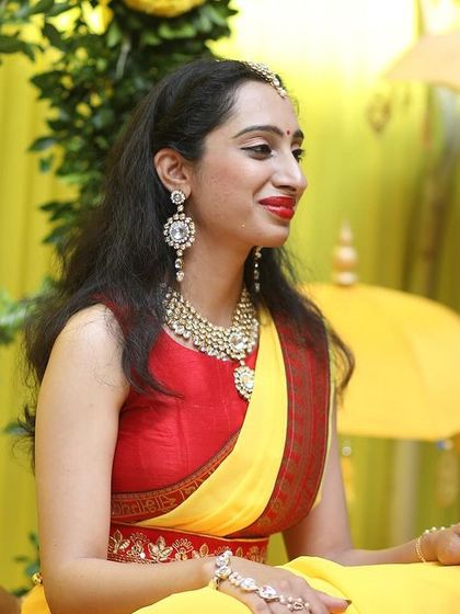 A moment of tradition during a Haldi ceremony, set against a backdrop of bright yellow drapes and marigold flowers.