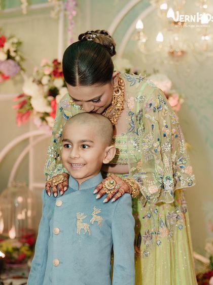 A tender moment captured between mother and son. He looks absolutely regal in his custom blue sherwani, a perfect outfit for his mundan ceremony.