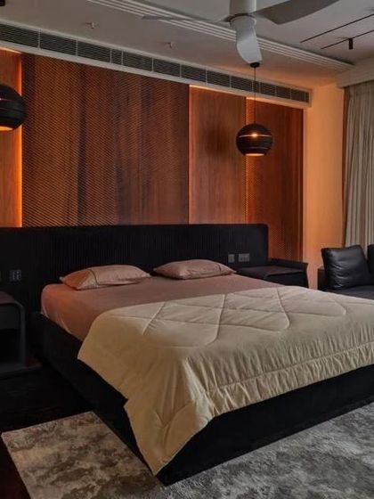 A bedroom that masterfully blends textures and tones. The warm wood paneling behind the bed, combined with soft backlighting, creates a cozy and inviting ambiance, perfect for a restful escape.