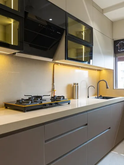 A closer look at our cappuccino-themed kitchen in Vile Parle. This shot highlights the flawless high-gloss finish on the handleless drawers, the sleek black sink, and the warm under-cabinet LED lighting that enhances the quartz countertop.