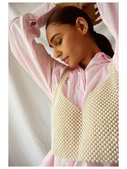 A throwback to a spring-themed fashion shoot. I layered a delicate pearl bralette over a classic pink button-down shirt, creating a look that is feminine, modern, and playful.