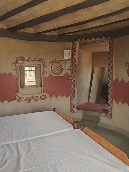 This bedroom shows the beauty of vernacular design, with its patterned mud-plastered walls, exposed ceiling beams, and deep-set windows. These traditional techniques naturally keep the interiors cool and comfortable.