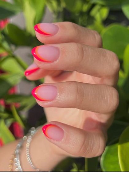 A vibrant double-layered French tip design with neon orange and pink. This style, known as a "shadow" or "outline" French, adds a modern, graphic pop of color.