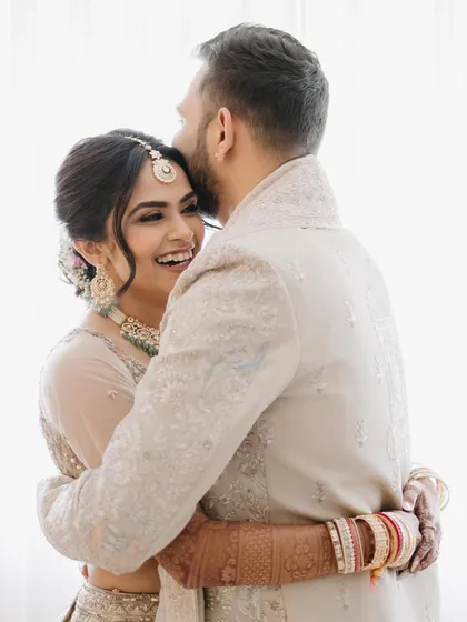 An intimate and joyful embrace between the bride and groom, showcasing a genuine moment of happiness and connection captured with a bright, airy feel.