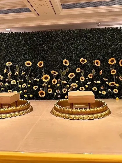 A simple and creative Haldi backdrop with a green wall and a field of sunflowers, perfect for an indoor or smaller space.