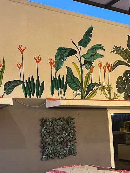 The full view of the large tropical mural, showing how it transforms an otherwise plain industrial wall into a vibrant work of art.