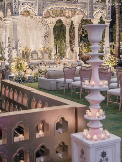 The warm glow of candles illuminates the intricate details of the mandap and guest seating, creating a deeply romantic and inviting atmosphere.