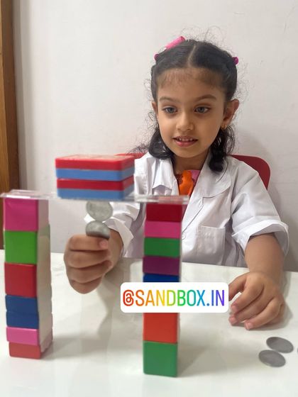 With a look of intense concentration, this girl adds another coin to the chain held by her magnetic bridge. It's a great hands-on lesson in magnetic strength and stability.