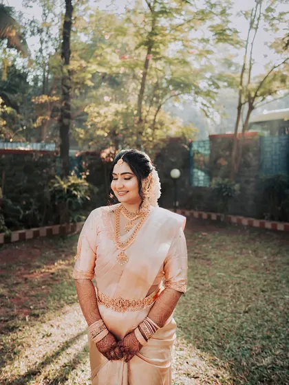 A full-length shot in a beautiful garden setting. The bride's classic attire and timeless makeup create a picture of pure grace.
