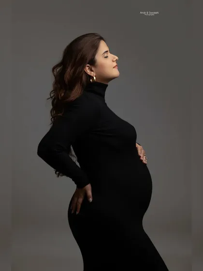 A moment of peace and connection. This classic profile shot in a simple black turtleneck dress beautifully accentuates the baby bump, creating a timeless and sophisticated portrait.