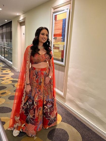 A bridesmaid looking absolutely stunning in a vibrant, multi-colored printed lehenga. The attached cape-style dupatta adds a modern and dramatic flair to the outfit.