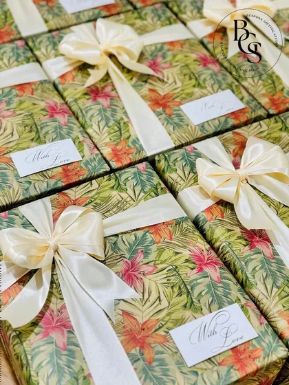 Gift wrapping is an art. These boxes, wrapped in a tropical floral print and tied with a classic cream satin bow, are perfect for a destination wedding or a summer event. The "With Love" tag adds a simple, personal touch.