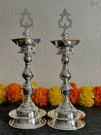Illuminate your sacred space with this pair of elegant silver diyas, also known as samay. Their polished finish and classic design make them a perfect addition to your pooja room or as a thoughtful housewarming gift.