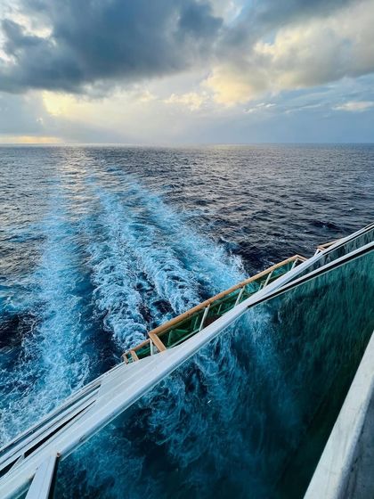 The wake of the cruise ship cutting through the ocean under a beautiful sky, a dynamic and compelling travel shot.