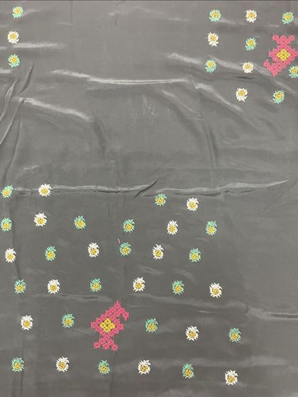 A grey silk fabric with small, colorful embroidered butis. This is a versatile design that can be used for both contemporary and traditional garments.