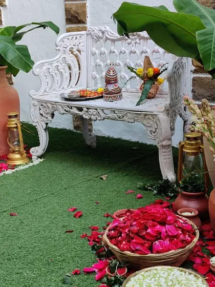 A beautiful and traditional decor corner. We used a vintage white bench, terracotta pots, banana plants, and baskets of fresh flower petals to create a lovely, rustic photo spot.